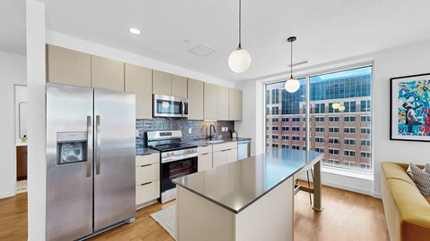 A modern kitchen with a stainless steel refrigerator and a large island.