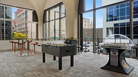 A foosball table is in the middle of a room with a pool table in the background.