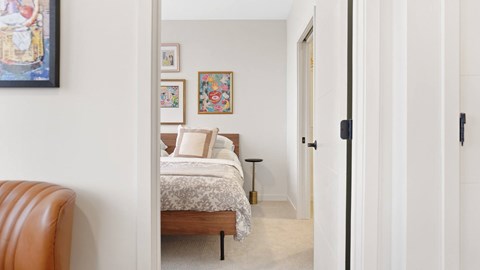 A bedroom with a bed, a chair, and pictures on the wall.
