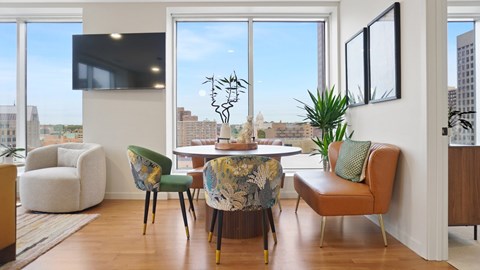 A living room with a large window and a TV on the wall.