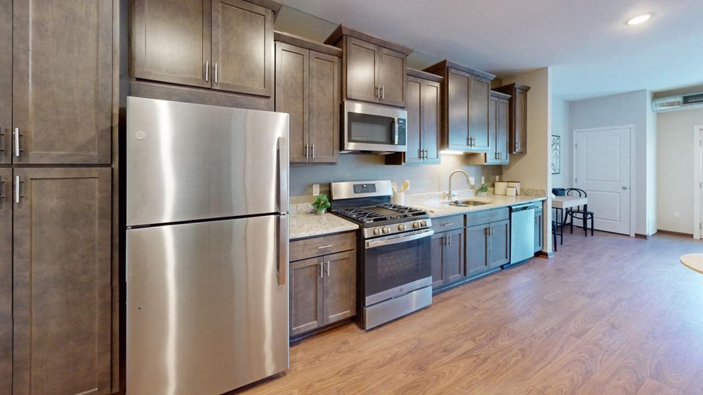 a kitchen with stainless steel appliances and wooden floors at The Yards and Backyards, South St. Paul