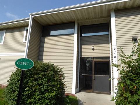A green sign with the word "OFFICE" on it is in front of a building.