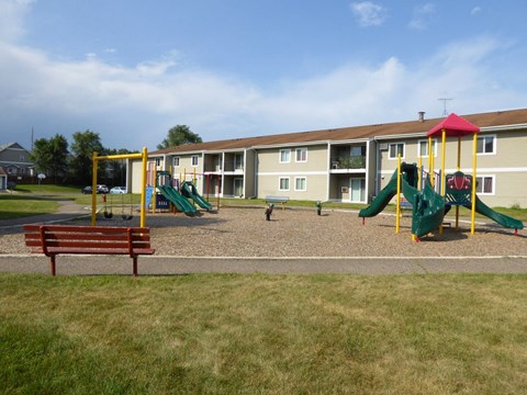 A playground with a green slide and a red and yellow structure.