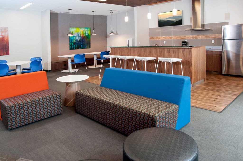 a lounge area with couches and chairs and a kitchen in the background