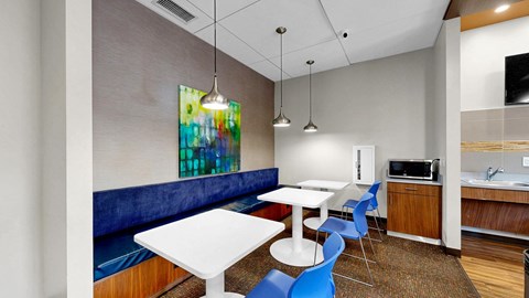 A modern dining area with a white table and blue chairs.