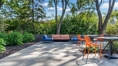 A patio with orange chairs and a blue bench.