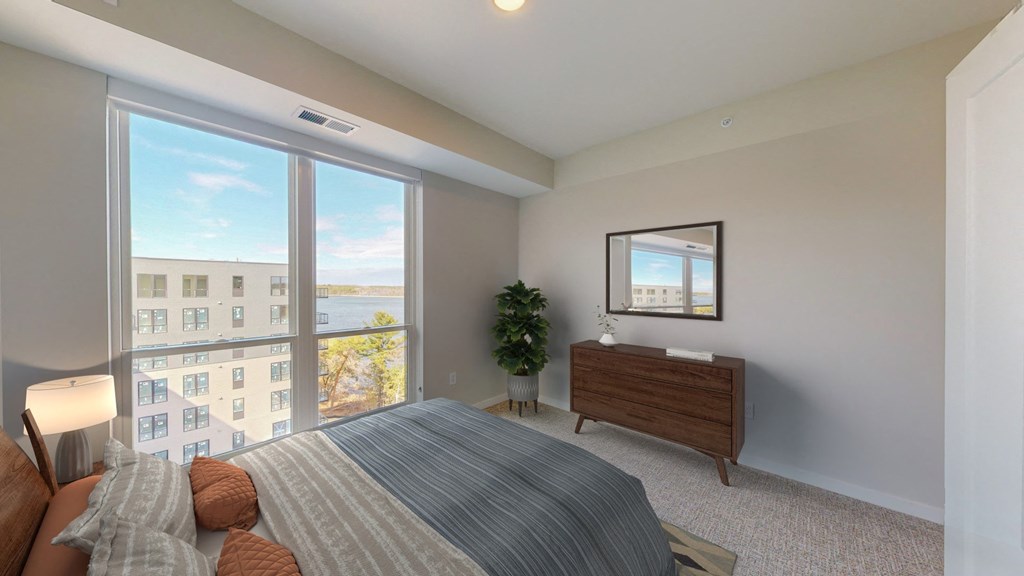 a bedroom with a large window and a bed and a dresser