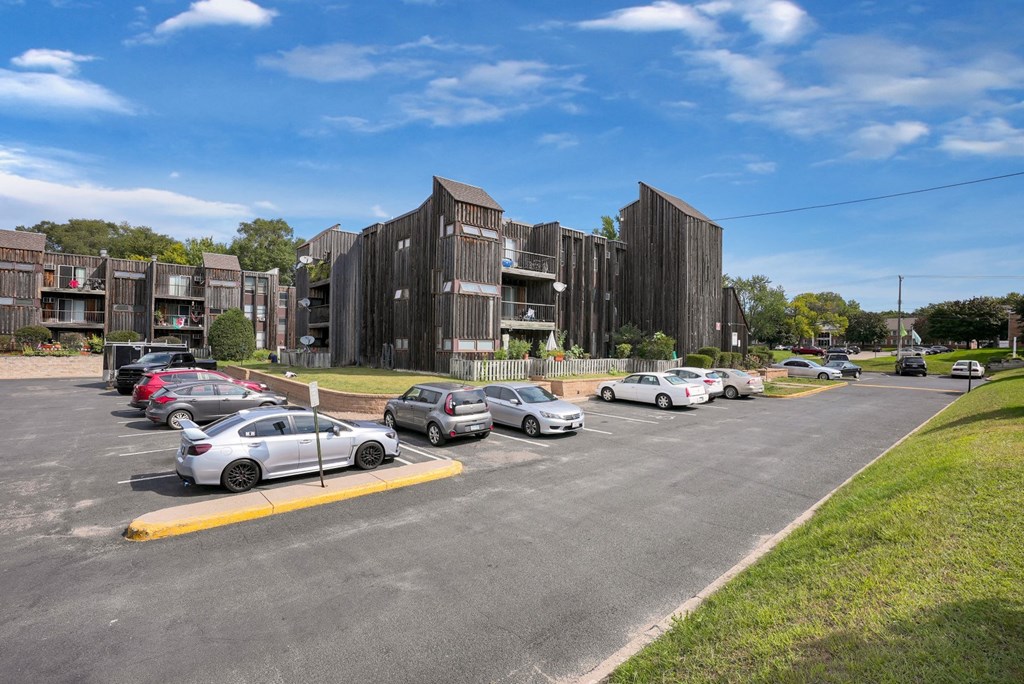 a parking lot with cars parked in front of apartment buildings