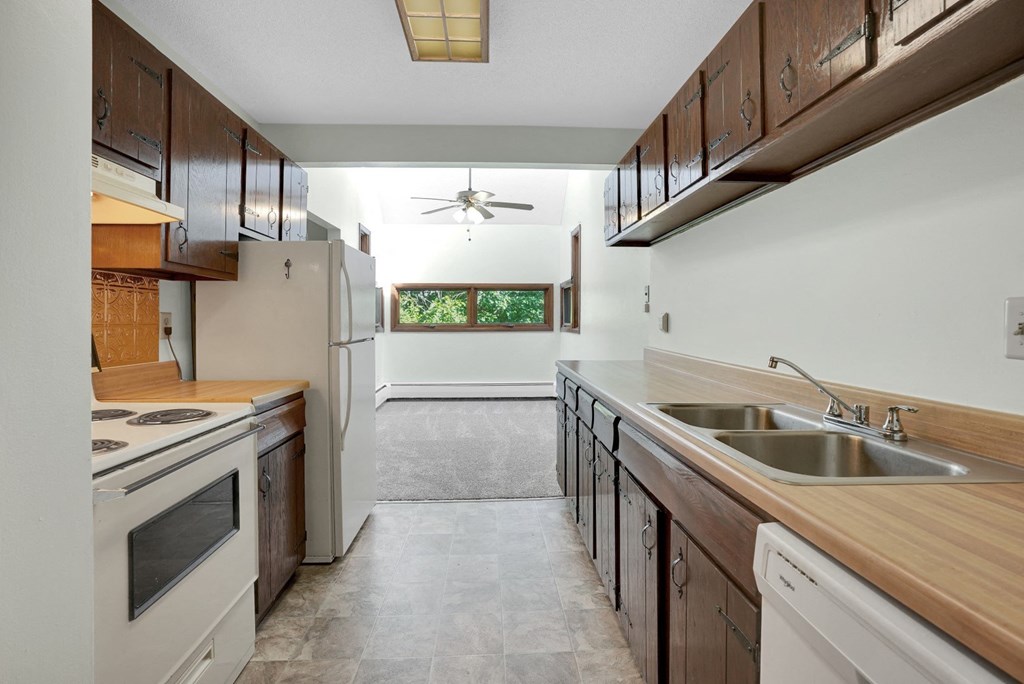 a kitchen with wooden cabinets and white appliances and a sink