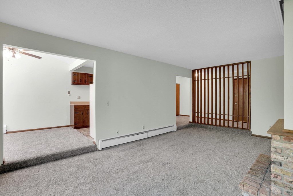 the living room and dining room of an empty house with white walls and a fireplace