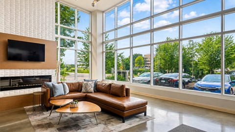 A living room with a brown leather couch and a flat screen TV mounted on the wall.