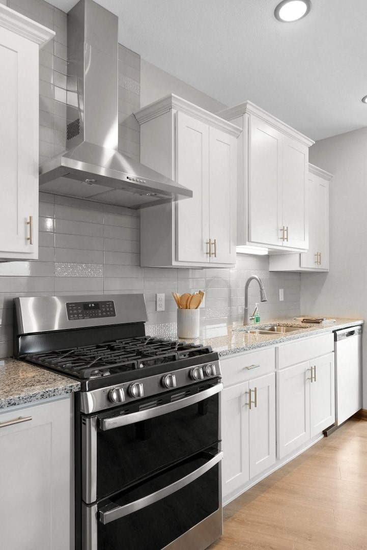 a white kitchen with stainless steel appliances and white cabinets at The Yards and Backyards, South St. Paul