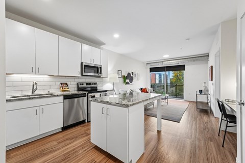 A modern kitchen with white cabinets and a wooden floor.