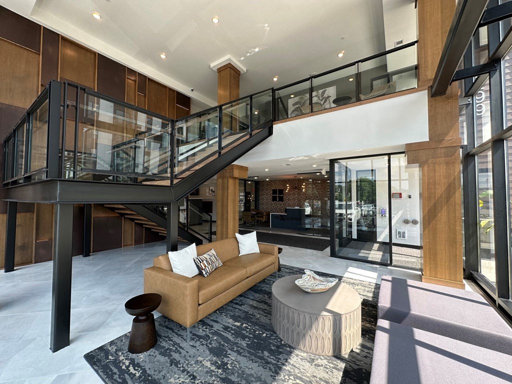 a large lobby with a staircase in the background and a couch and coffee table in the