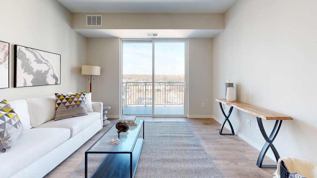 a living room with a white couch and coffee table and a sliding glass door leading to a