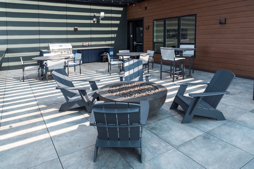 an outdoor patio with a fire pit and tables and chairs