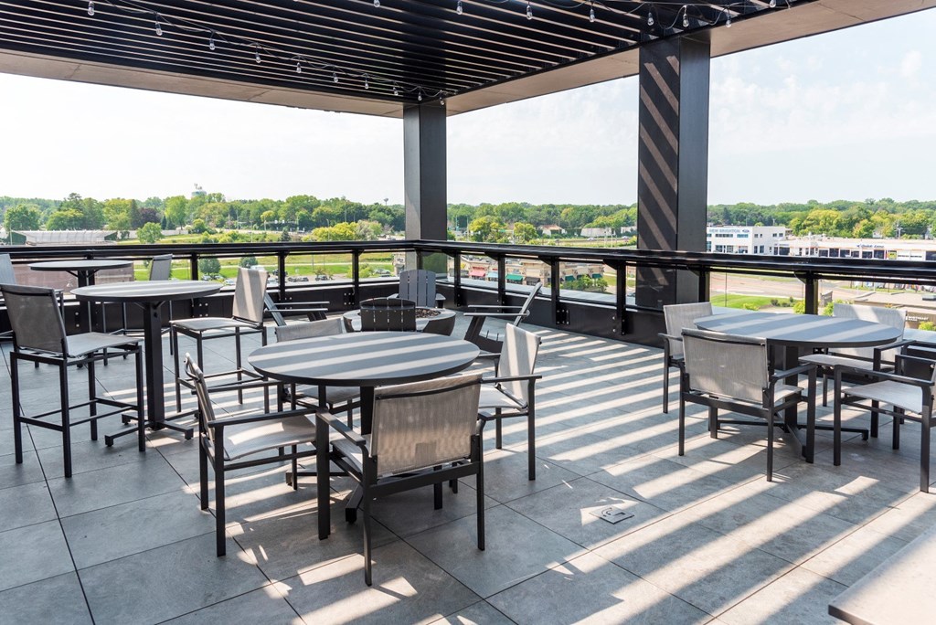 a patio with tables and chairs and a view of a river