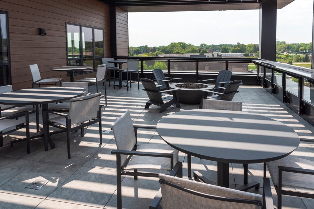 a patio with tables and chairs overlooks a body of water