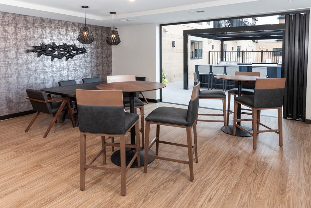 a communal area with tables and chairs and a bar in the background