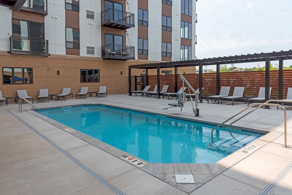 a swimming pool with chaise lounge chairs and a building in the background