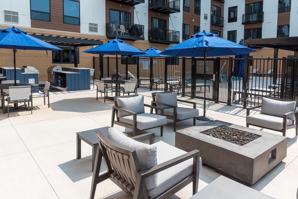 a patio with chairs and umbrellas and a firepit