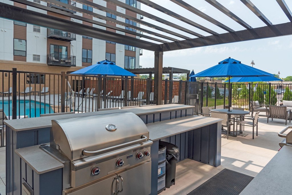 a patio with a grill and tables with umbrellas