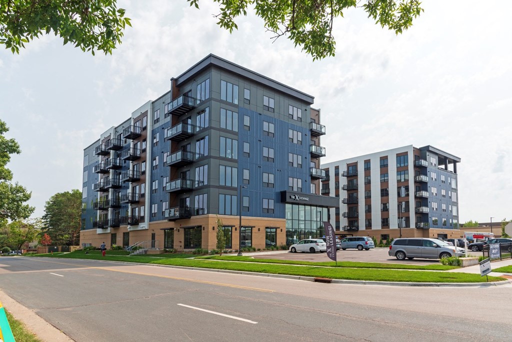 a view from the street of two buildings with cars parked in front of them