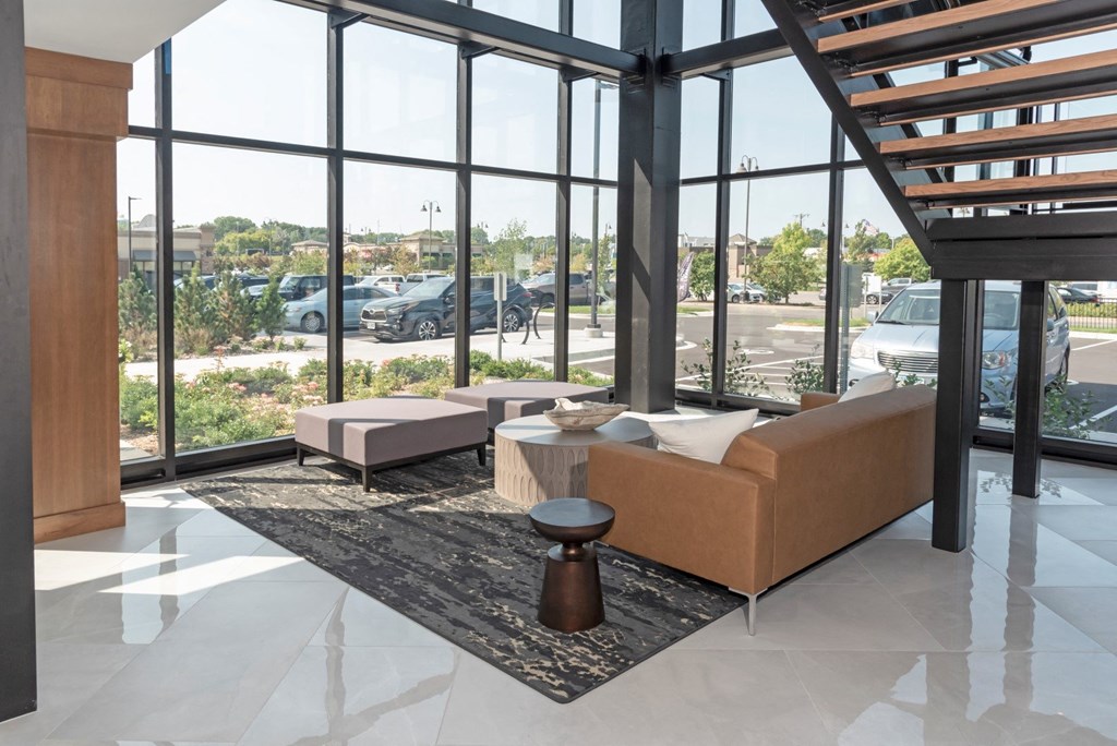 a living room with a couch and chairs in front of a wall of windows