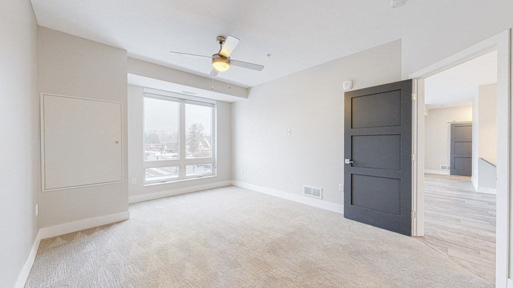 a bedroom with a large window and a ceiling fan