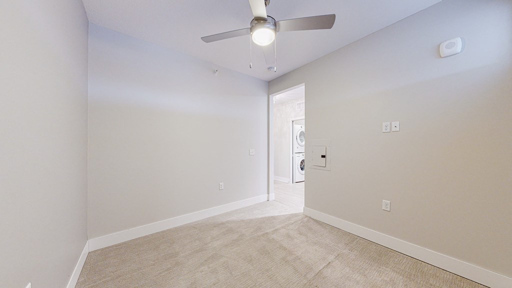 a bedroom with white walls and a ceiling fan