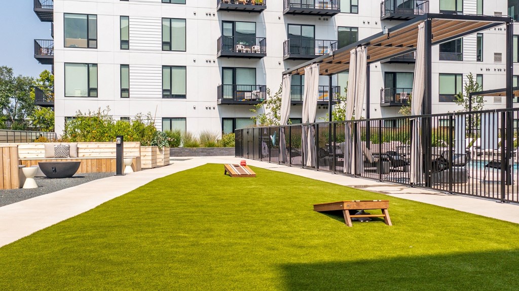 a grassy area with two benches in front of an apartment building
