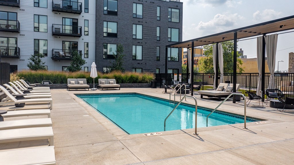 a swimming pool with chaise lounge chairs and a building in the background