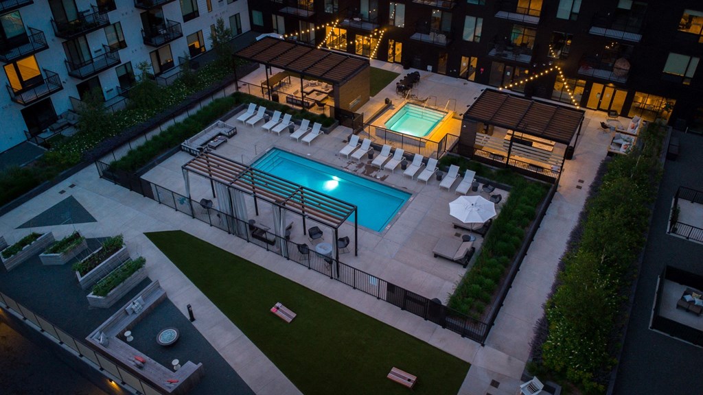 a pool and lounge chairs in a yard of an apartment building