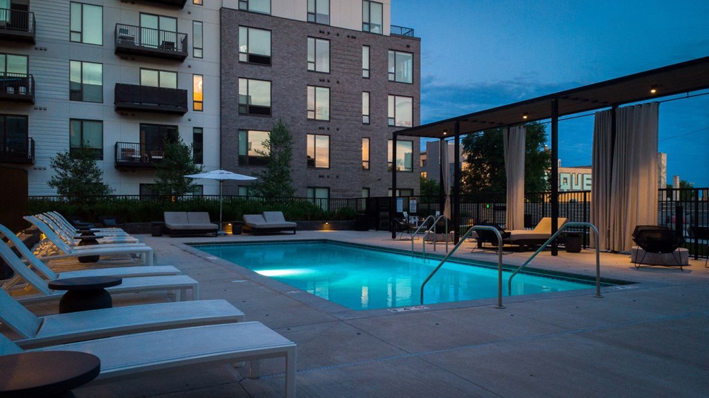 a swimming pool at night in front of an apartment building