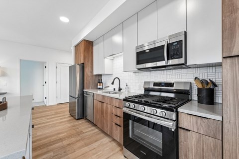 A modern kitchen with a black stove top oven and white cabinets.