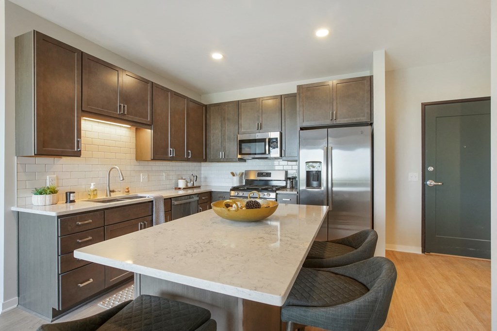 a kitchen with dark wood cabinets and a white island with a wooden bowl on top of it