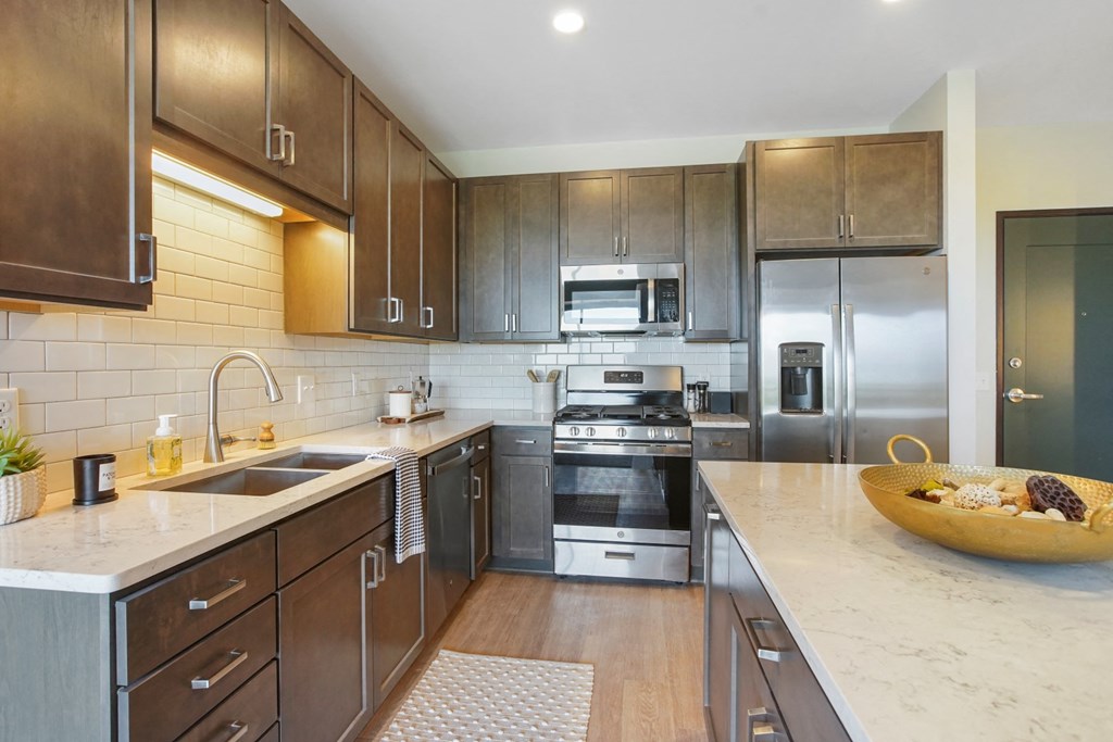 a kitchen with dark wood cabinets and white countertops