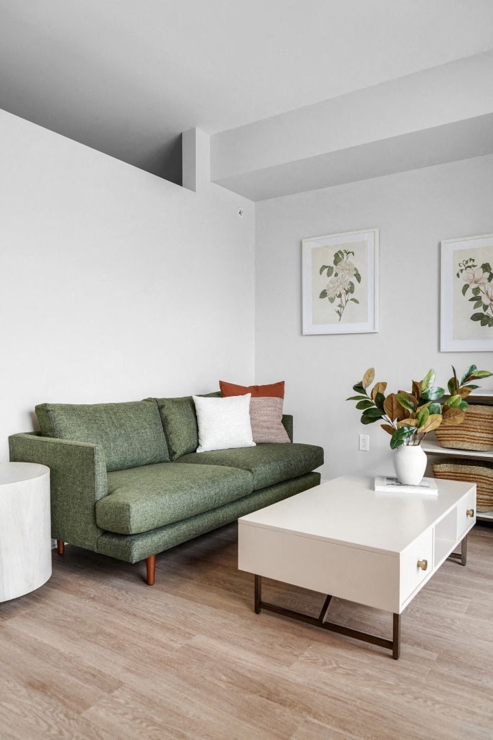 a living room with a green couch and a white coffee table
