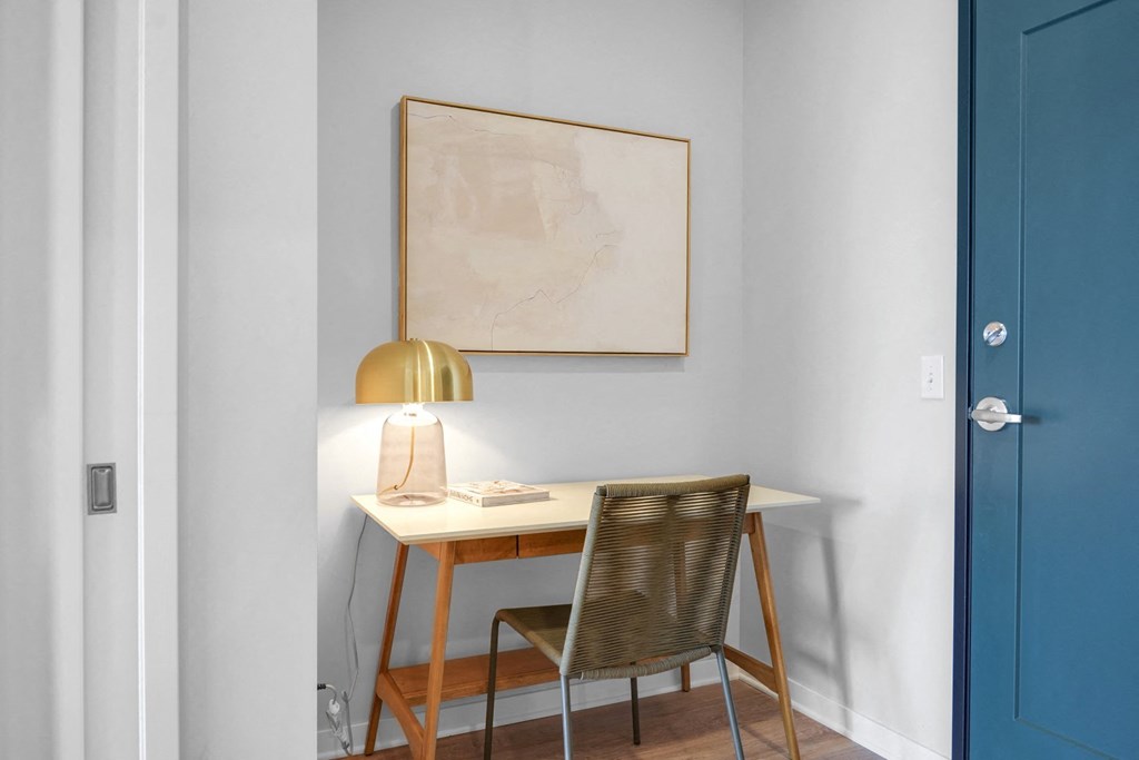 a small desk with a lamp and a book on it in a room with a blue door