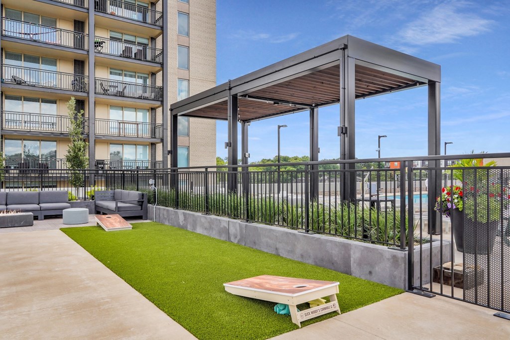 a patio with a table and chairs and a pergola in front of an apartment building