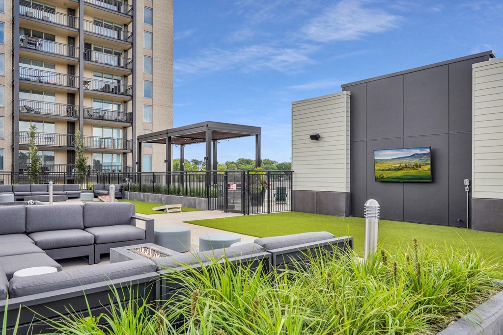 a grassy area with couches and a fire pit in front of an apartment building
