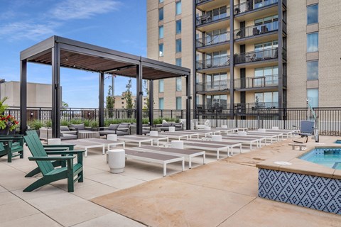 an outdoor lounge area with lounge chairs and umbrellas at the melrose apartments at The Gateway at West Lake Quarter in Minneapolis, MN