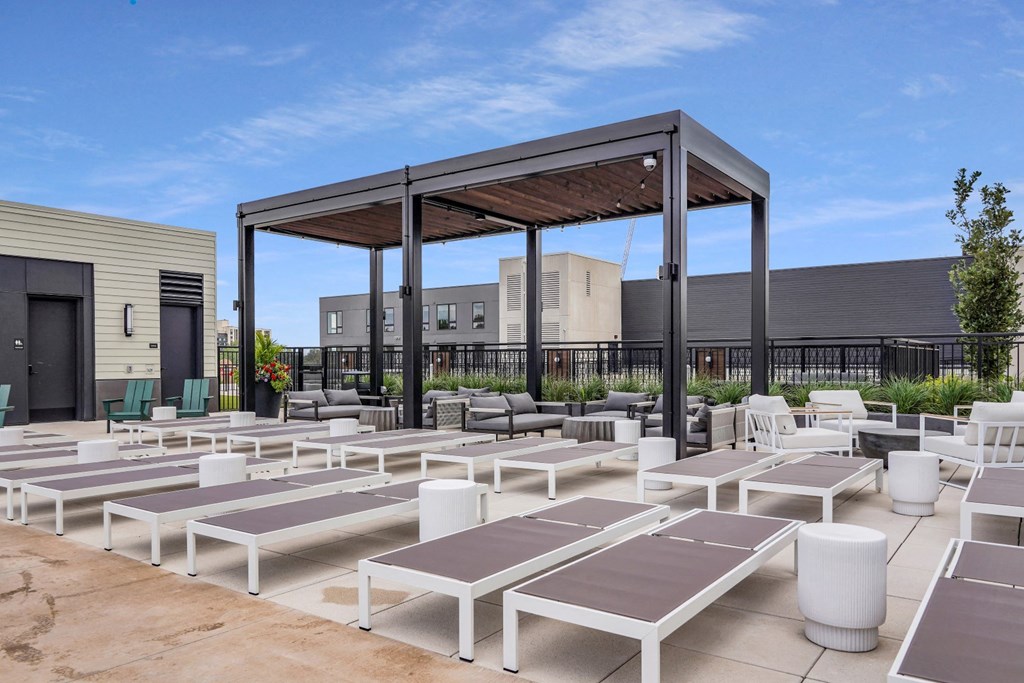 a group of white lounge chairs and umbrellas on a patio with buildings in the background