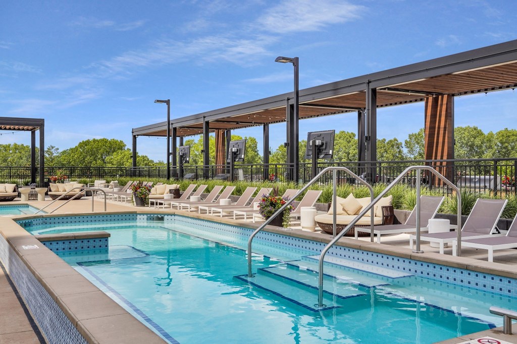 a resort style pool with lounge chairs and a pergola