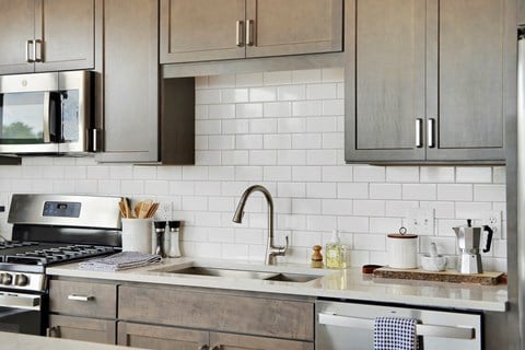 a kitchen with gray cabinets and white tile