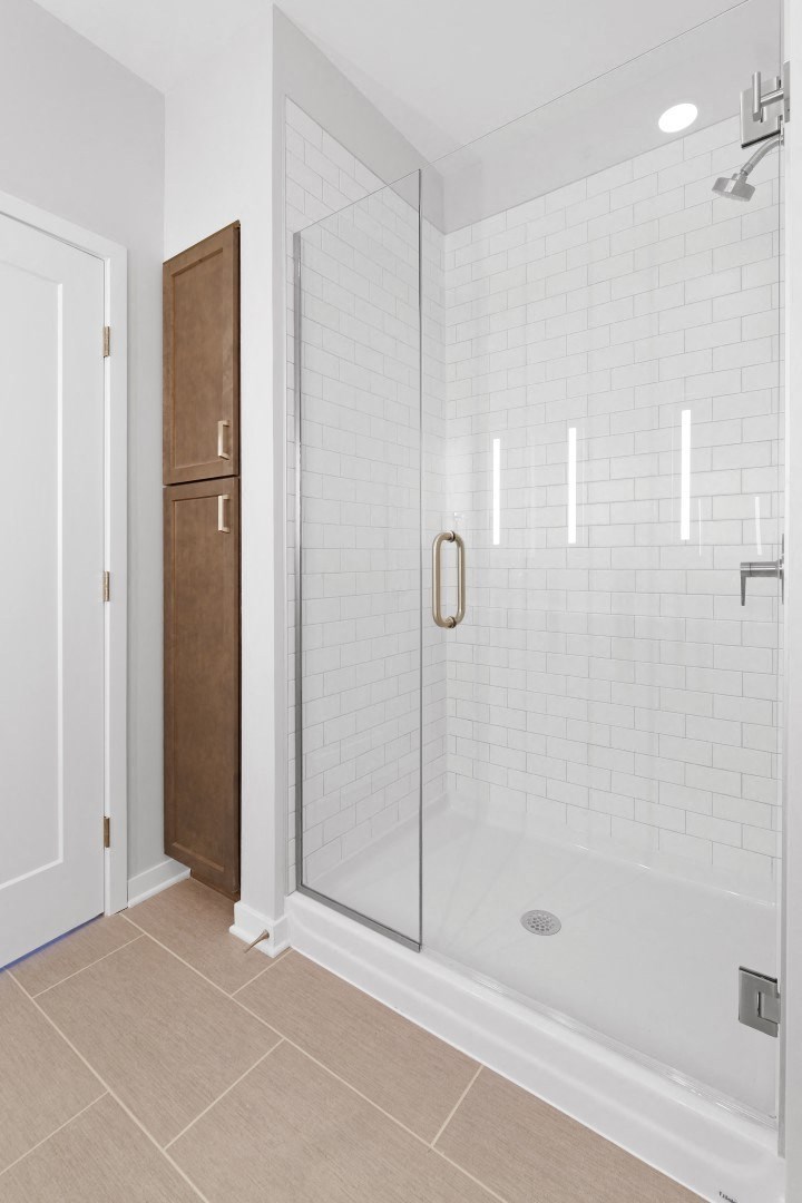 a bathroom with white tiles and a glass shower door