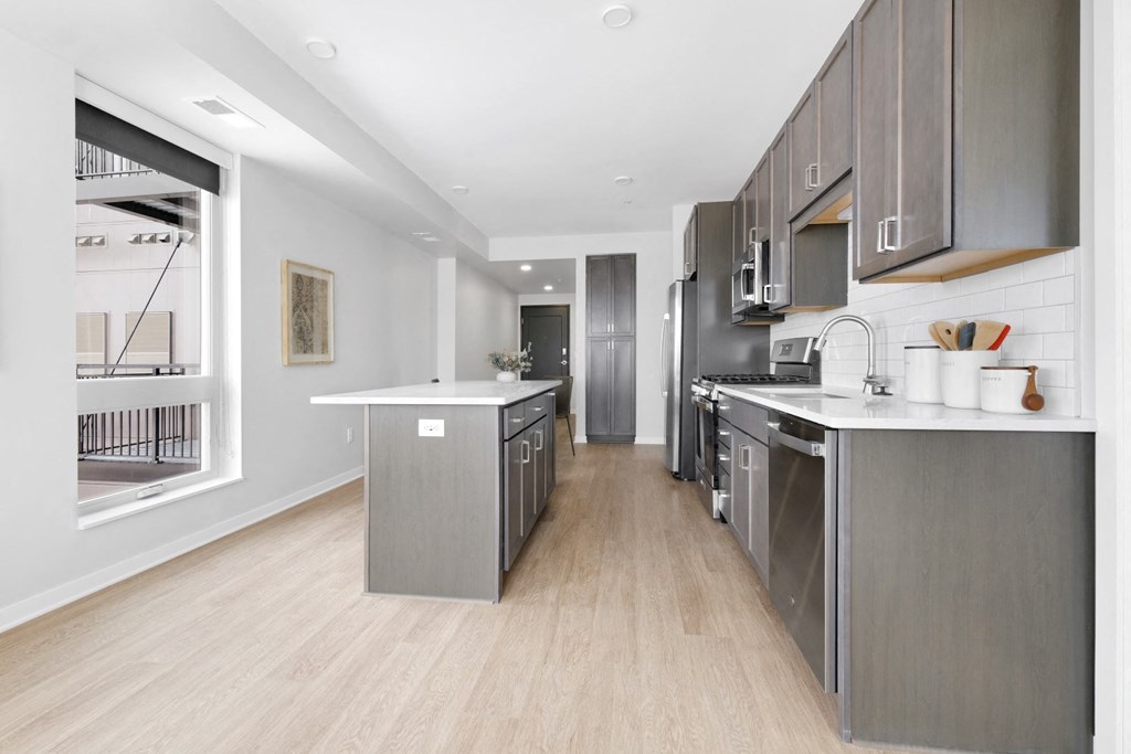 a kitchen with gray cabinetry and white countertops