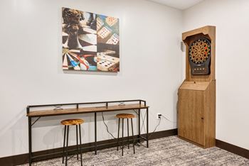 a table with stools and a clock in a room with a painting on the wall