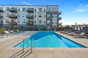 an apartment complex with a swimming pool and chaise lounge chairs