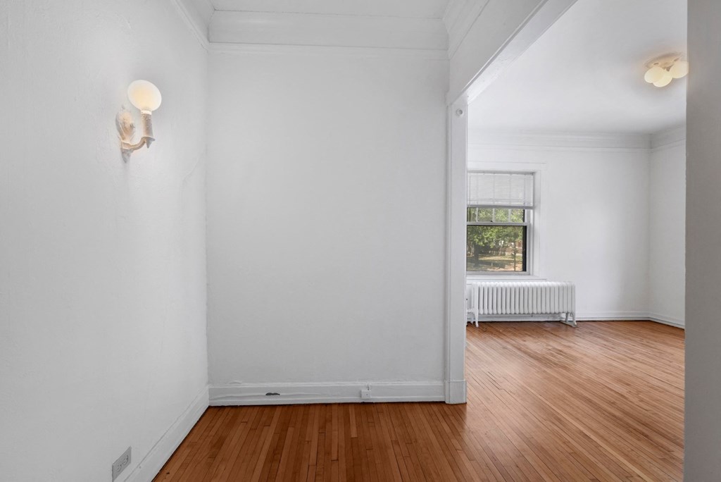 a bedroom with white walls and hardwood floors